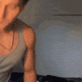 a man in a white tank top stands in front of a wall
