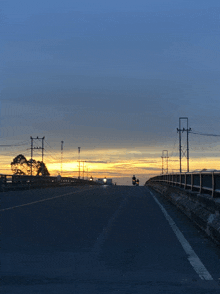 a bridge over a highway with a sunset behind it