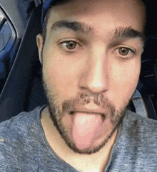 a man with a beard sticking out his tongue in a car