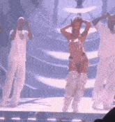 a woman in a cowboy outfit is dancing with two men on a stage