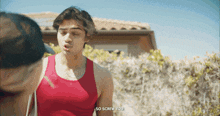 a man in a red tank top says " so screw you " to another man