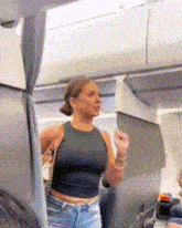 a woman in a black tank top and blue shorts is standing in a plane .