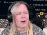a woman wearing headphones and a scarf is sitting in front of a screen that says norge