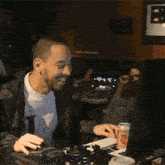 a man is smiling while using a computer with a can of orange soda next to him