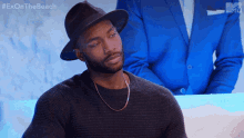 a man wearing a hat and a sweater with the hashtag exonthe beach on the bottom