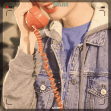 a woman in a denim jacket is talking on a telephone with the word mint on the bottom