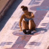 a woman in a bikini is sitting on a colorful surface with a few letters on it .