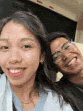 a man and a woman are posing for a picture and the man is wearing glasses