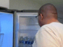 a man in a white shirt is looking into a fridge