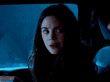 a woman is sitting in the back seat of a car and looking at the camera