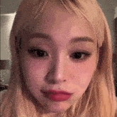 a close up of a woman 's face with long blonde hair and red lips .