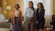 three women standing in a hotel room with a netflix logo