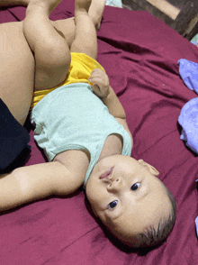 a baby laying on a bed with a purple blanket