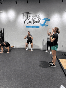 a group of people are doing exercises in front of a wall that says fitness collab on it