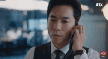 a man in a suit and tie is talking on a cell phone with jtbc in the corner