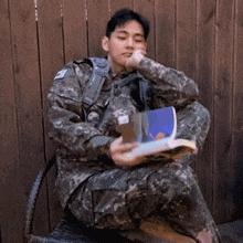 a man in a camouflage uniform is reading a book