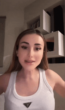 a woman is wearing a white tank top with a prada logo on it