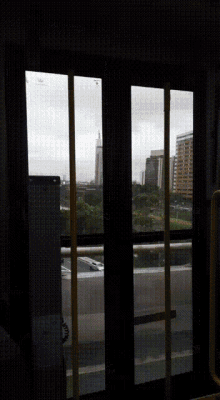 a view of a city through a window with a yellow handle