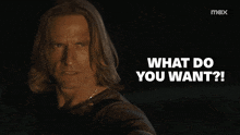 a man with long hair is looking at the camera with the words what do you want below him