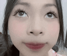 a close up of a woman 's face with long eyelashes and a pink lip .