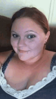 a woman is sitting on a couch wearing a bra and smiling .