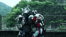 two monsters are standing next to each other in front of a fence with trees in the background