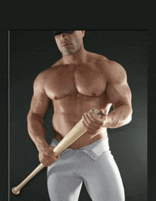 a shirtless man holds a baseball bat in his hands