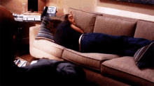a man is laying on a couch in a living room with a laptop on it .