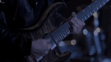 a man in a leather jacket is playing an electric guitar in a dark room .