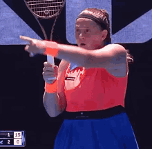 a woman is holding a tennis racquet and pointing at something while playing tennis .