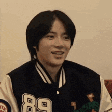 a young man wearing a varsity jacket is smiling .