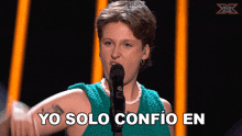 a woman singing into a microphone with yo solo confio en written on the bottom