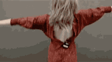 a woman in a red dress is standing with her arms outstretched and her back to the camera .