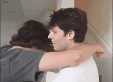 two young men hugging each other in front of a door .