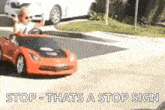 a little boy is driving a toy car on a street .