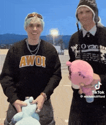 two men are holding stuffed animals in a parking lot .
