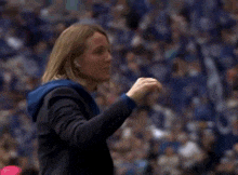 a woman in a suit is standing in front of a crowd and waving