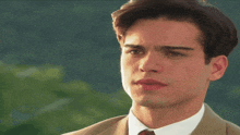 a young man in a suit and tie is looking at something