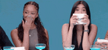 two women covering their mouths while holding a piece of paper that says " i 'm "