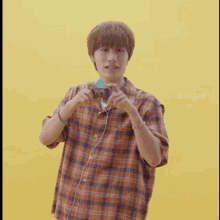 a man in a plaid shirt is taking a picture with a yellow background and the words byd land below him