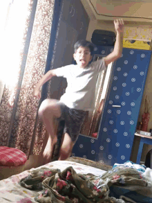 a boy is jumping in the air in front of a blue cabinet