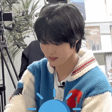 a young man wearing a blue and white sweater is looking at something