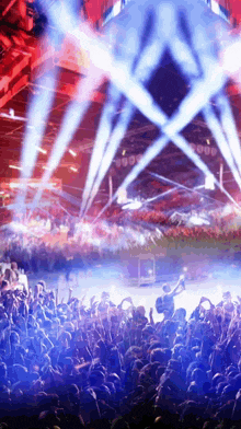 a crowd of people at a concert with blue and red lights shining on them