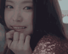 a close up of a woman 's face with her hands on her face and a sequined top .