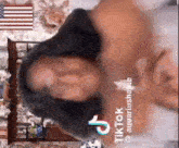 a woman is laying on a bed with her arms outstretched in front of a wall with an american flag .