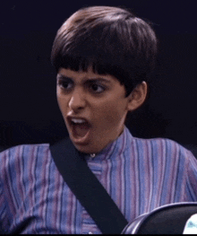 a young boy in a striped shirt is making a funny face with his mouth open