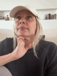 a woman wearing a hat and a black sweater is making a funny face