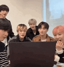 a group of young men are looking at a laptop computer together .