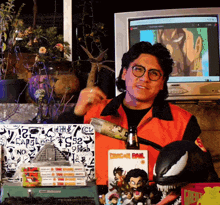 a man in an orange jacket is standing in front of a stack of books including one that says dragon ball
