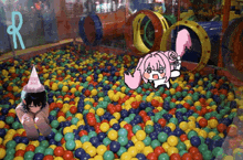 a girl in a party hat is sitting in a ball pit